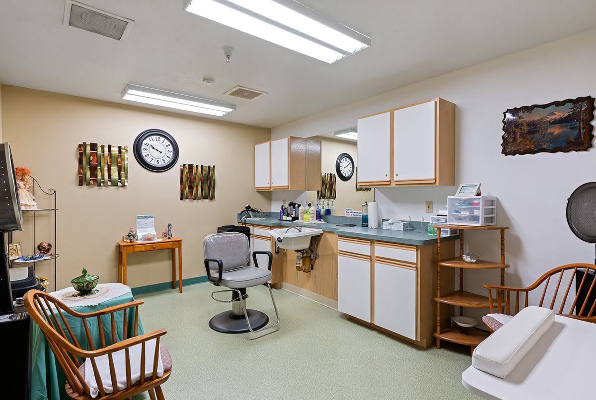 Interior of a hair salon with a chair, mirrors, and clock.