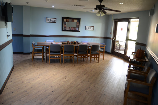 A spacious dining room featuring a long wooden table surrounded by chairs, complemented by light blue walls and ample natural light.