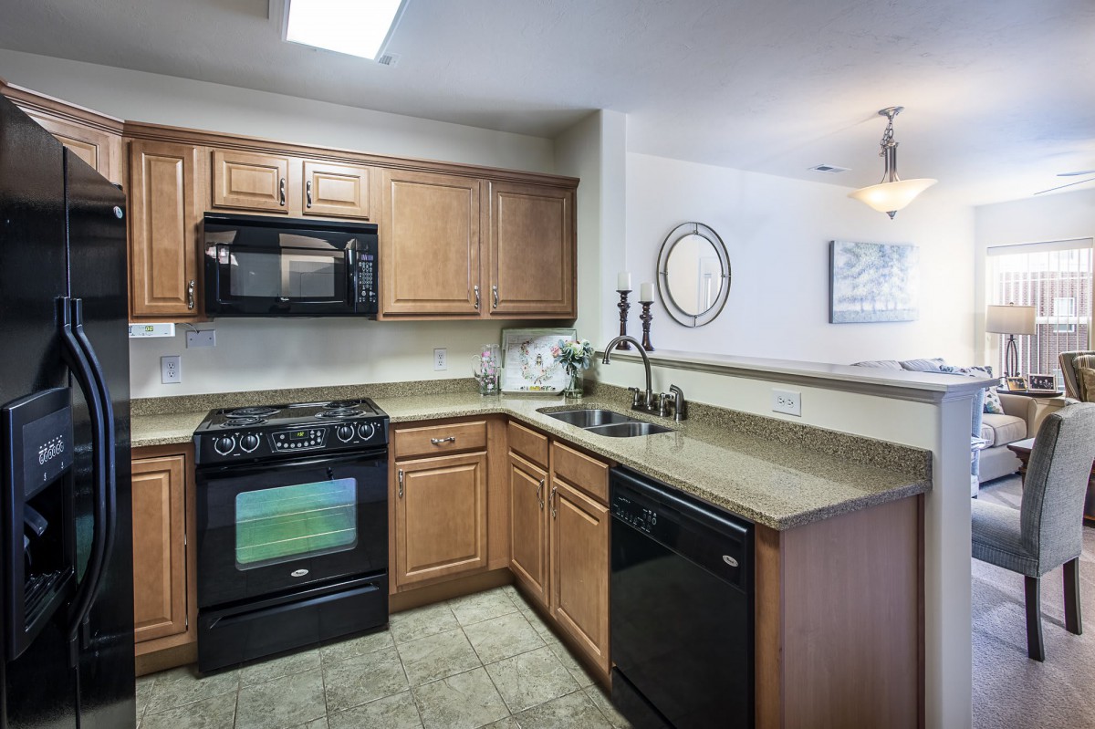 A modern kitchen with wooden cabinets, a countertop, and appliances including a stove and microwave.