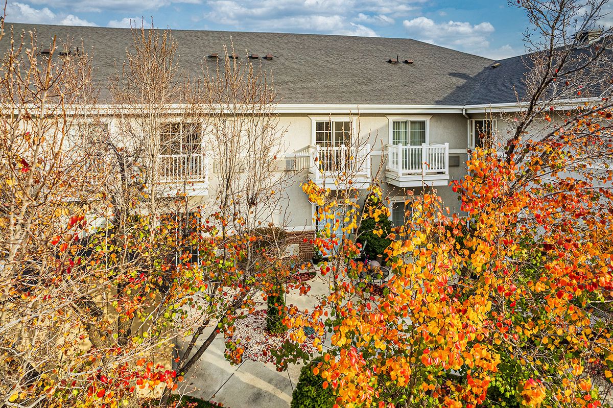A view of a building with balconies surrounded by trees in autumn foliage.