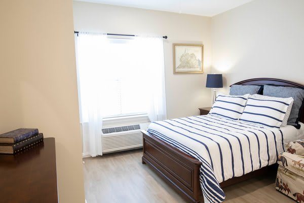 A cozy bedroom with a striped bedspread and natural light flowing through a window.