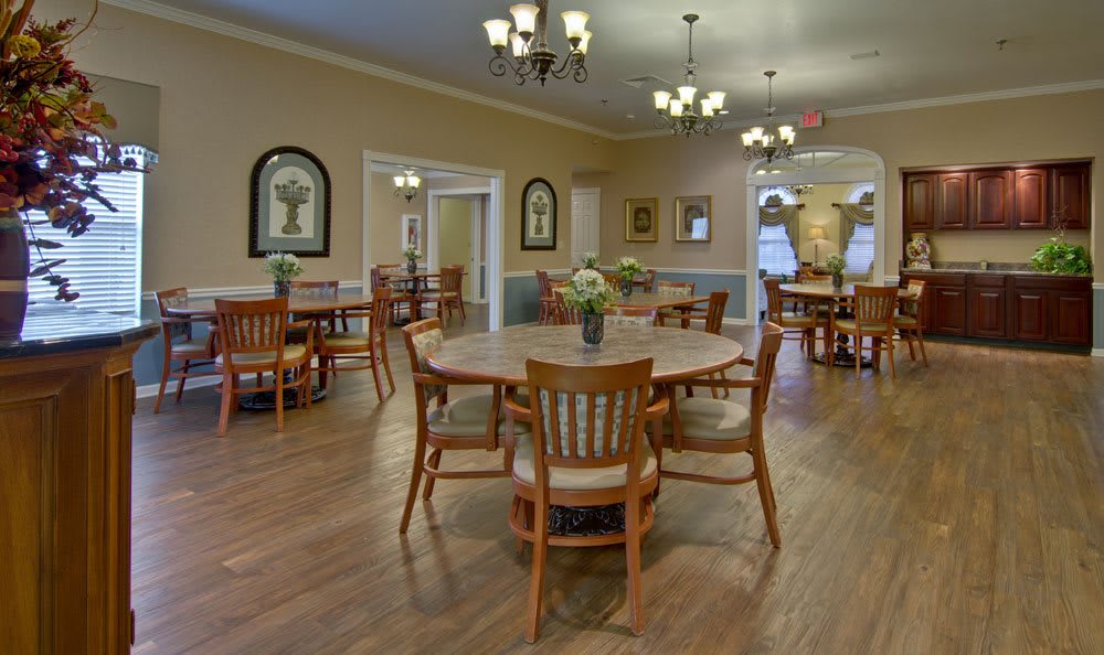 A spacious dining area with wooden tables and chairs, decorated with elegant lighting and wall art.