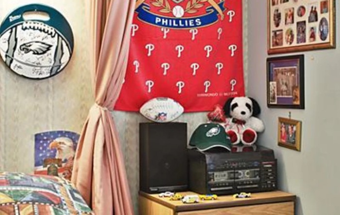 A room decorated with Philadelphia Phillies memorabilia, featuring a banner, stuffed animal, and sports gear.