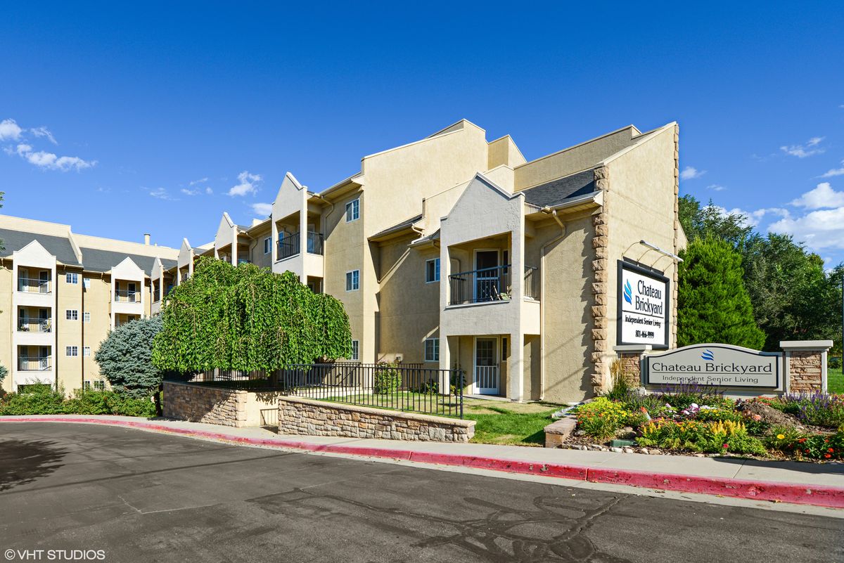A modern apartment building with well-maintained landscaping and clear blue sky.