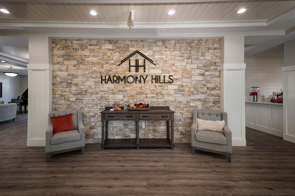 A cozy waiting area with two chairs, a table, and a brick wall featuring the 'Harmony Hills' signage.
