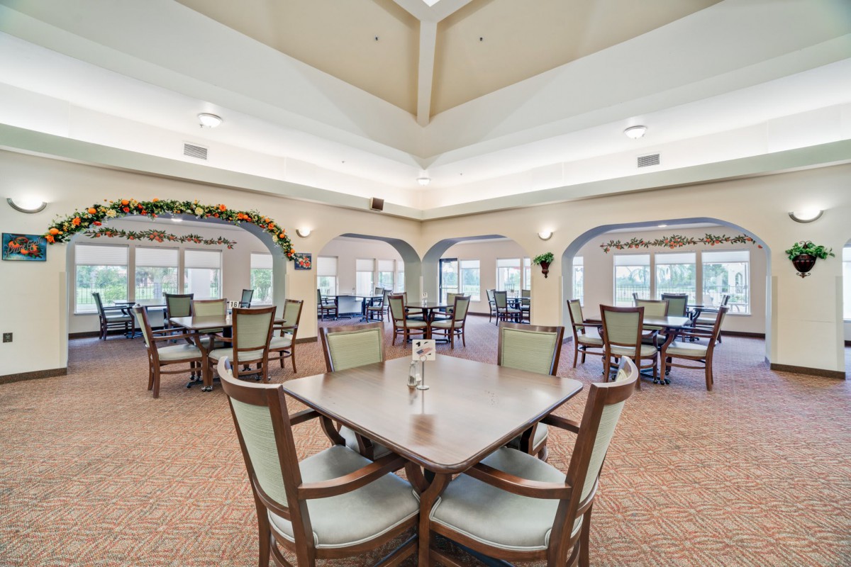 A spacious dining area featuring multiple tables and chairs, with elegant lighting and decor.