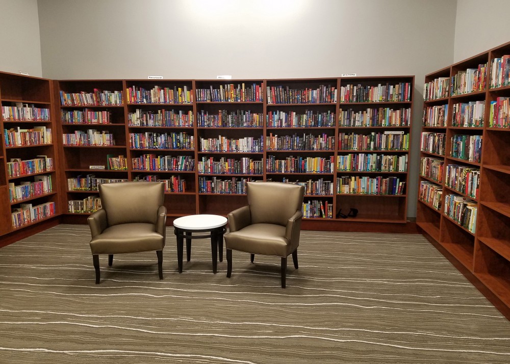 A cozy reading area with two chairs and a small table in front of bookshelves filled with books.