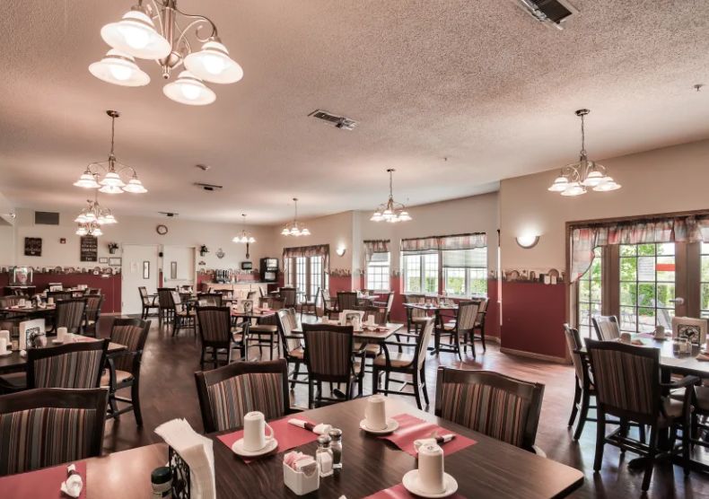 An elegantly arranged dining area with multiple tables, chairs, and chandeliers.