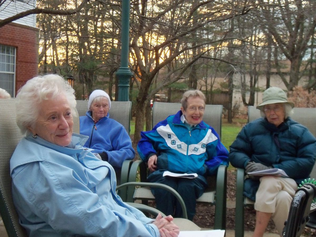 A group of seniors sitting outdoors, enjoying a casual gathering in autumn.