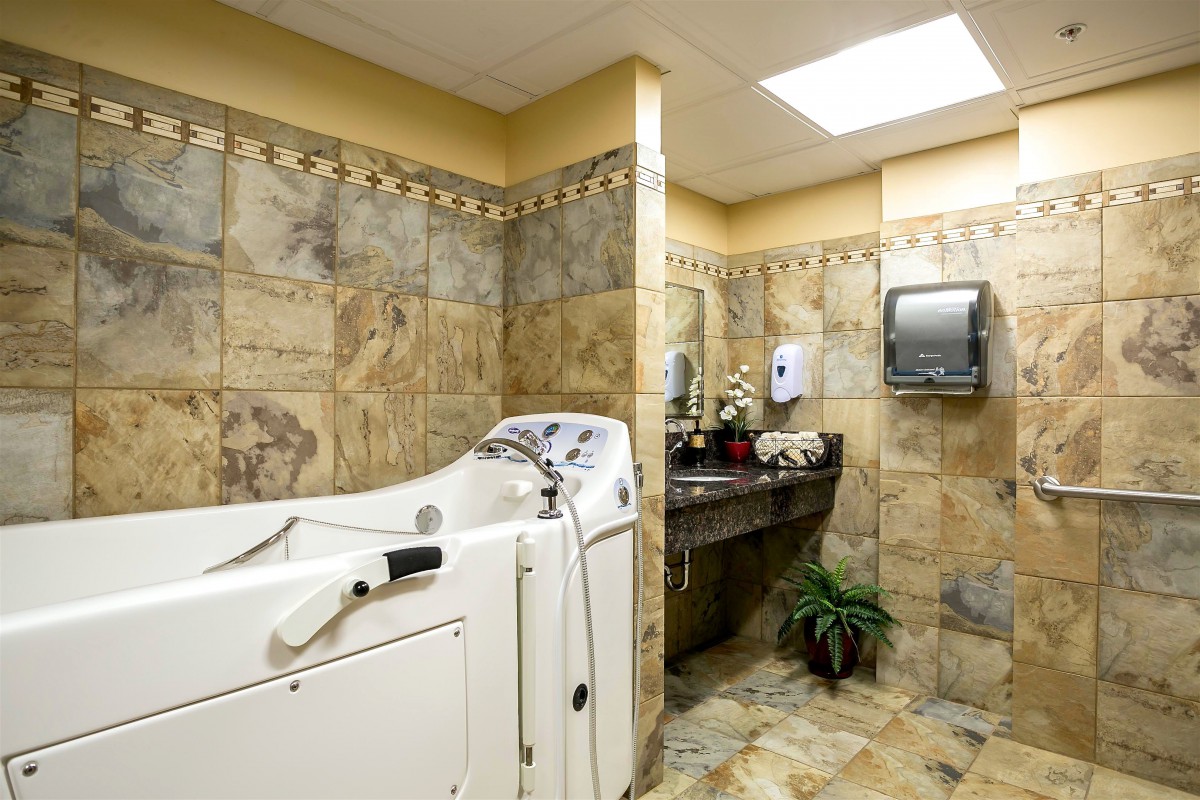 A spacious bathroom with a walk-in tub and decorative tiles.