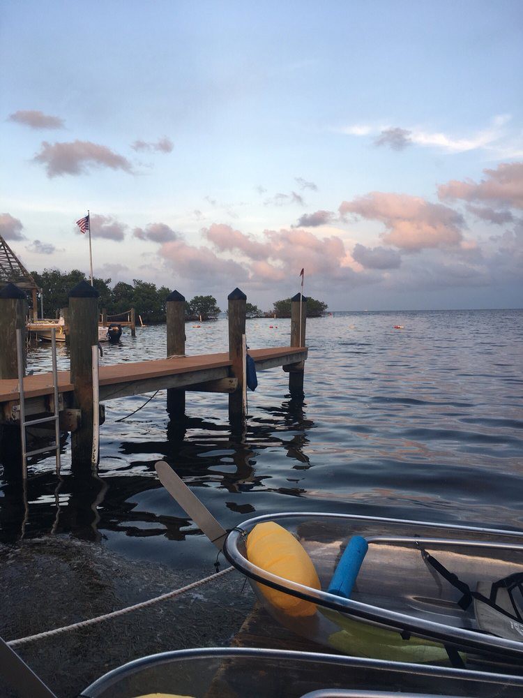 A serene lake view at sunset with a dock and boat in the foreground.