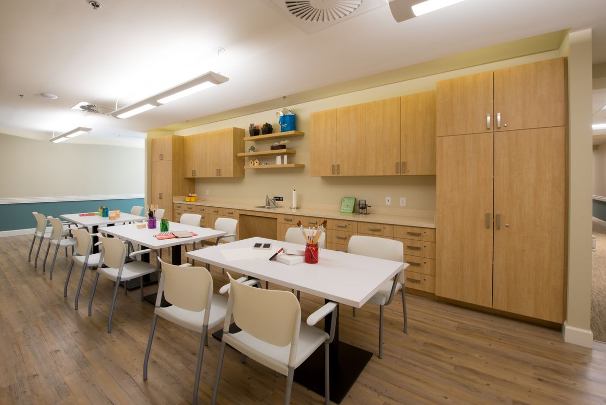 A modern kitchen interior with wooden cabinets, a large table, and chairs.