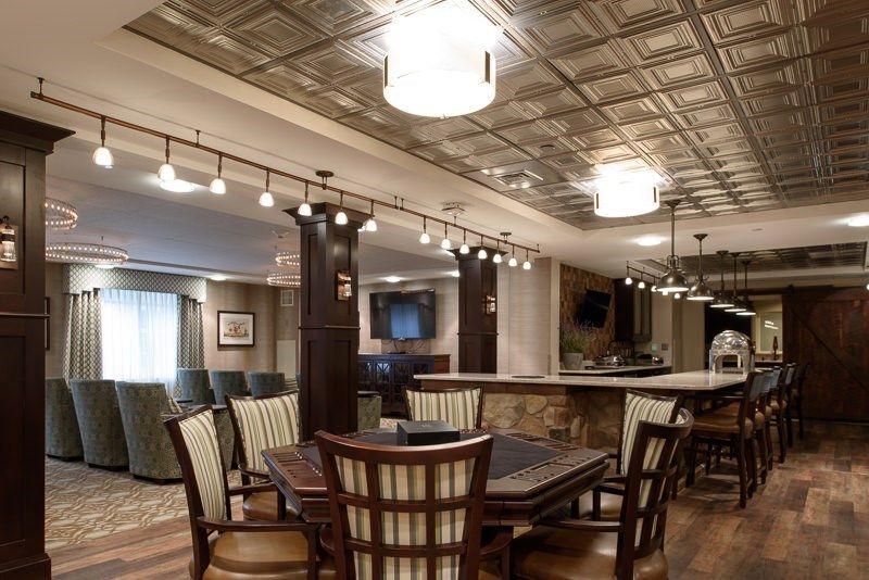 A stylish and cozy dining area with a bar, featuring modern pendant lighting and wooden furniture.
