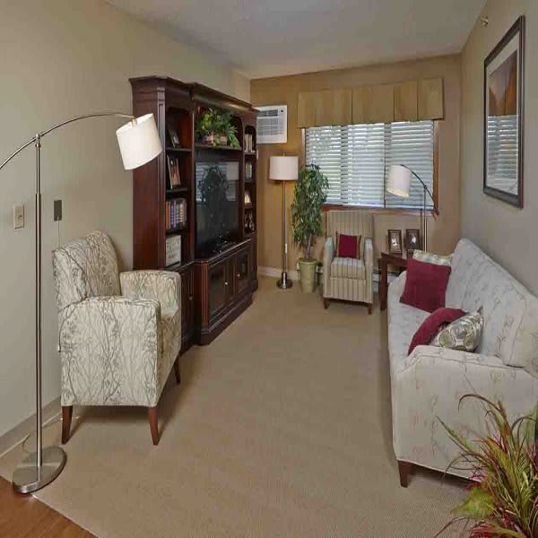 A cozy living room with a sofa, armchairs, a television set, and decorative elements.