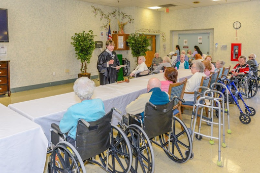 A community gathering at a care facility, where elderly residents engage in a presentation.