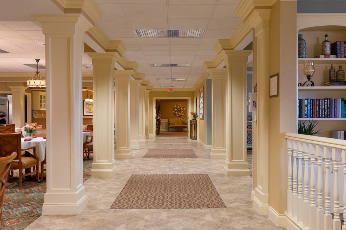 A well-lit interior hallway with columns and carpeting.