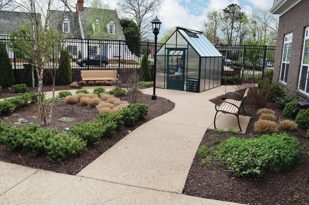 A peaceful garden scene with a greenhouse, a winding pathway, and a bench for relaxation.