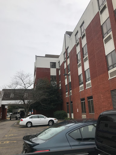 A view of a brick hotel building with a parking area under a cloudy sky.