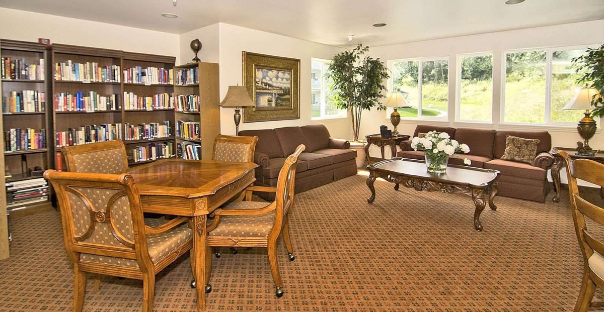 A cozy living room with a sofa, coffee table, bookshelf, and seating area.