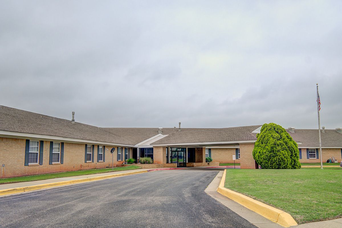 A single-story building with a central entrance and surrounding driveway on a cloudy day.