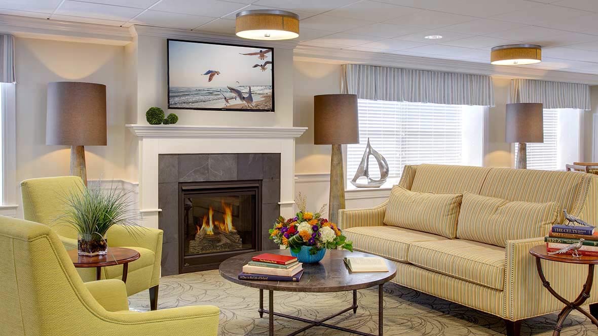 A cozy living room with a fireplace, featuring comfortable seating and decorative elements.