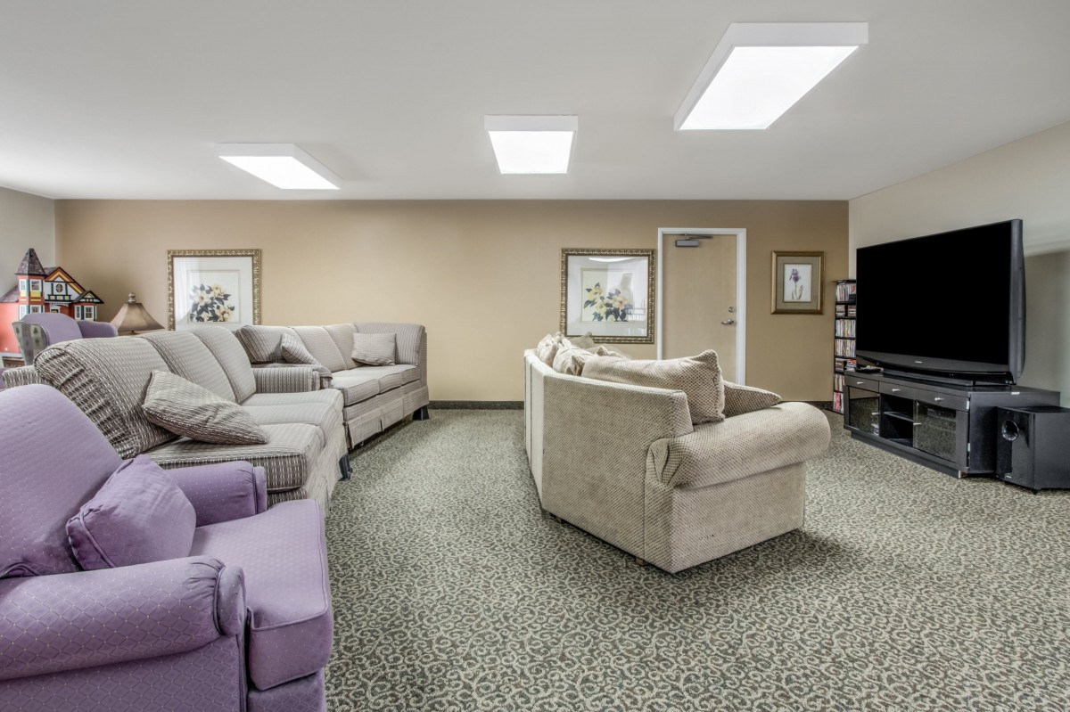 A spacious living room with multiple sofas and a large television.