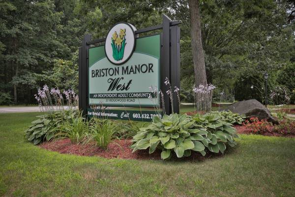 A sign for Briarcliff Manor West surrounded by lush foliage and landscaping.