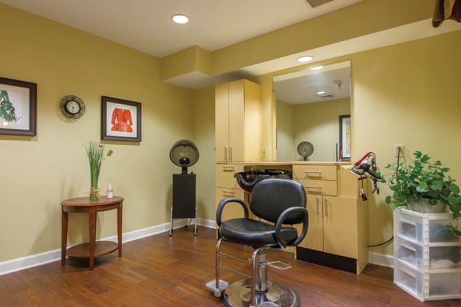 A modern hair salon setup featuring a styling chair and mirror, complemented by sleek cabinetry and warm decor.