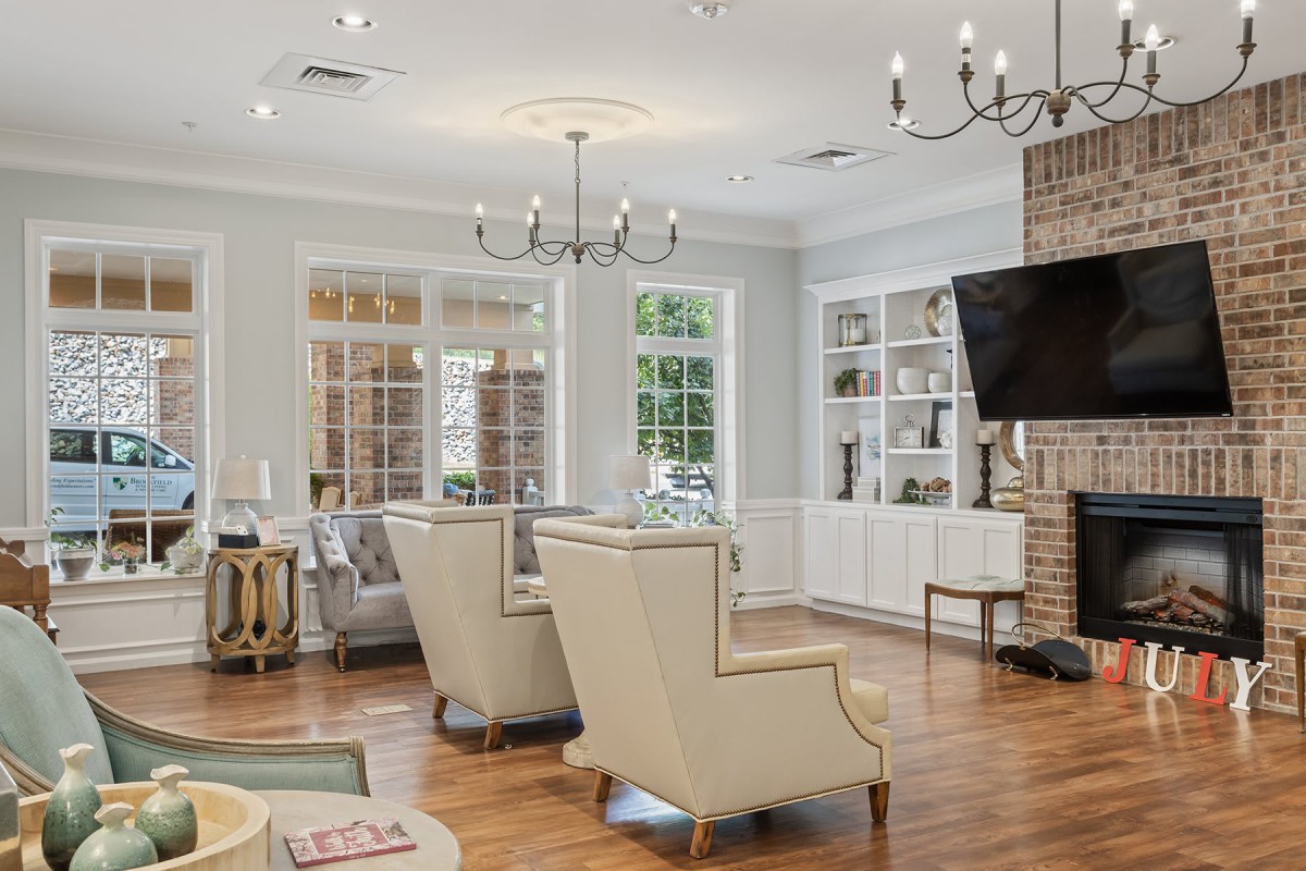 A modern living room with elegant furniture, large windows, and a mounted television.