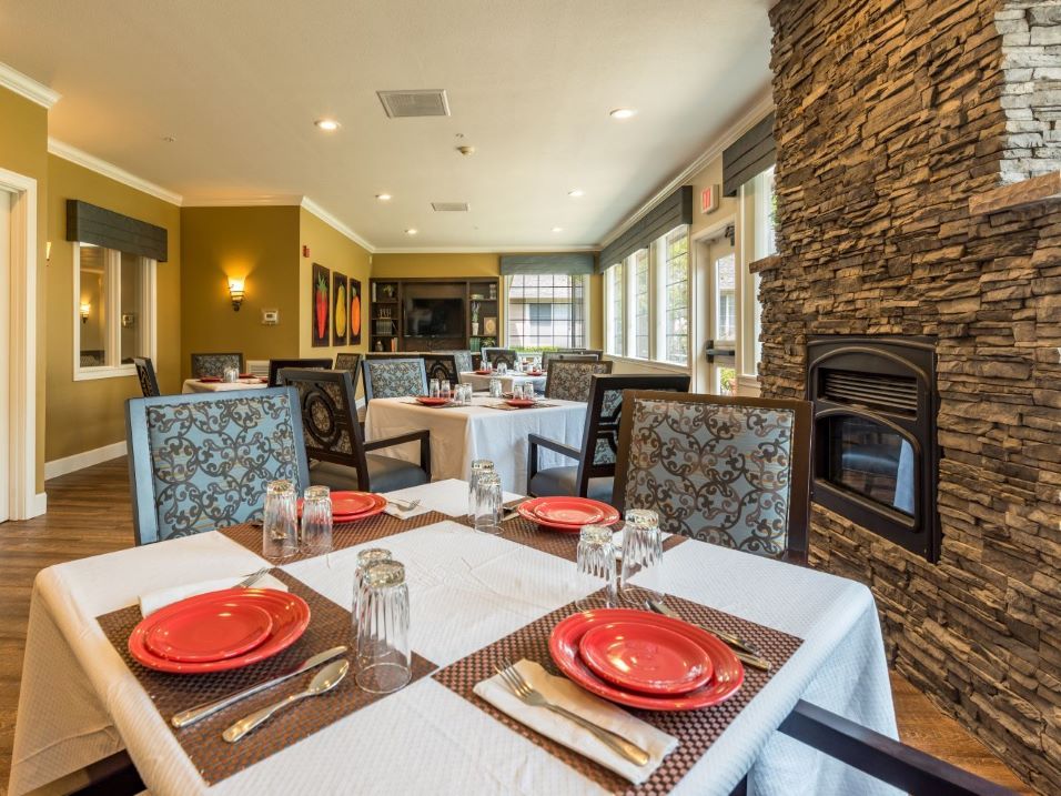 A modern dining room with a cozy fireplace and elegantly set tables.
