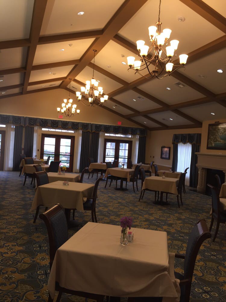 An elegant dining room with neatly arranged tables and chandeliers.