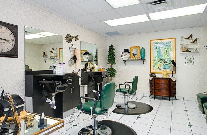 An interior view of a hair salon with green chairs and mirrored stations.