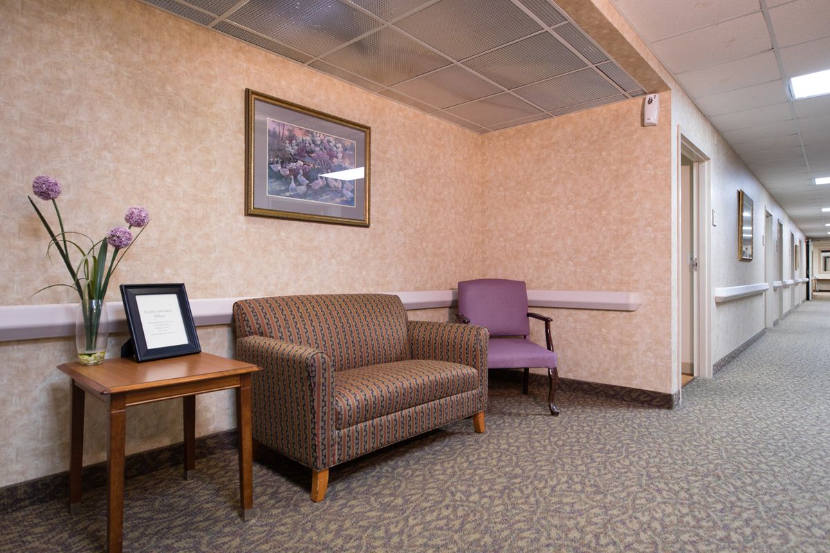 A cozy waiting room with a sofa, chair, and framed artwork on the wall.