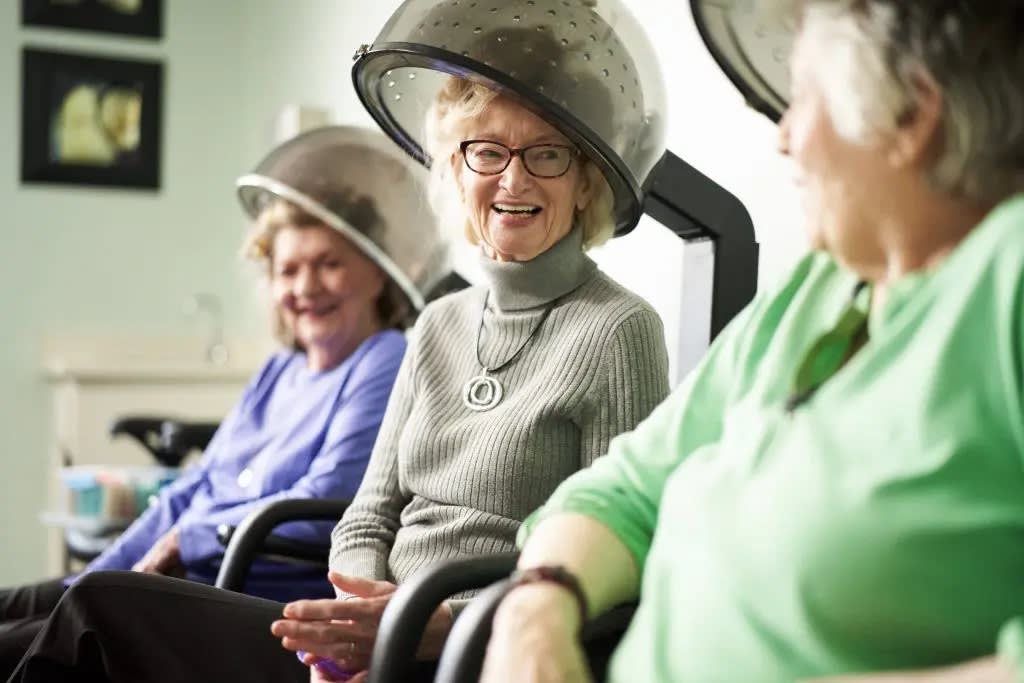 Elderly women enjoying a relaxing conversation under hair dryers at a salon.