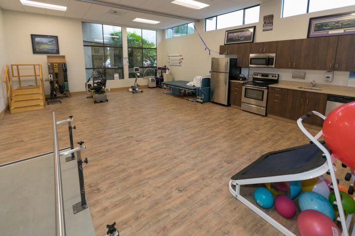 A spacious physical therapy room equipped with exercise equipment and fitness balls.