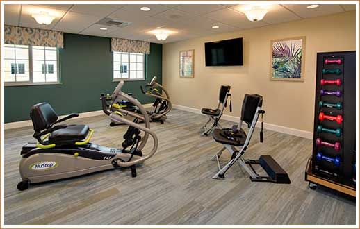A modern gym with exercise machines and a mounted TV.