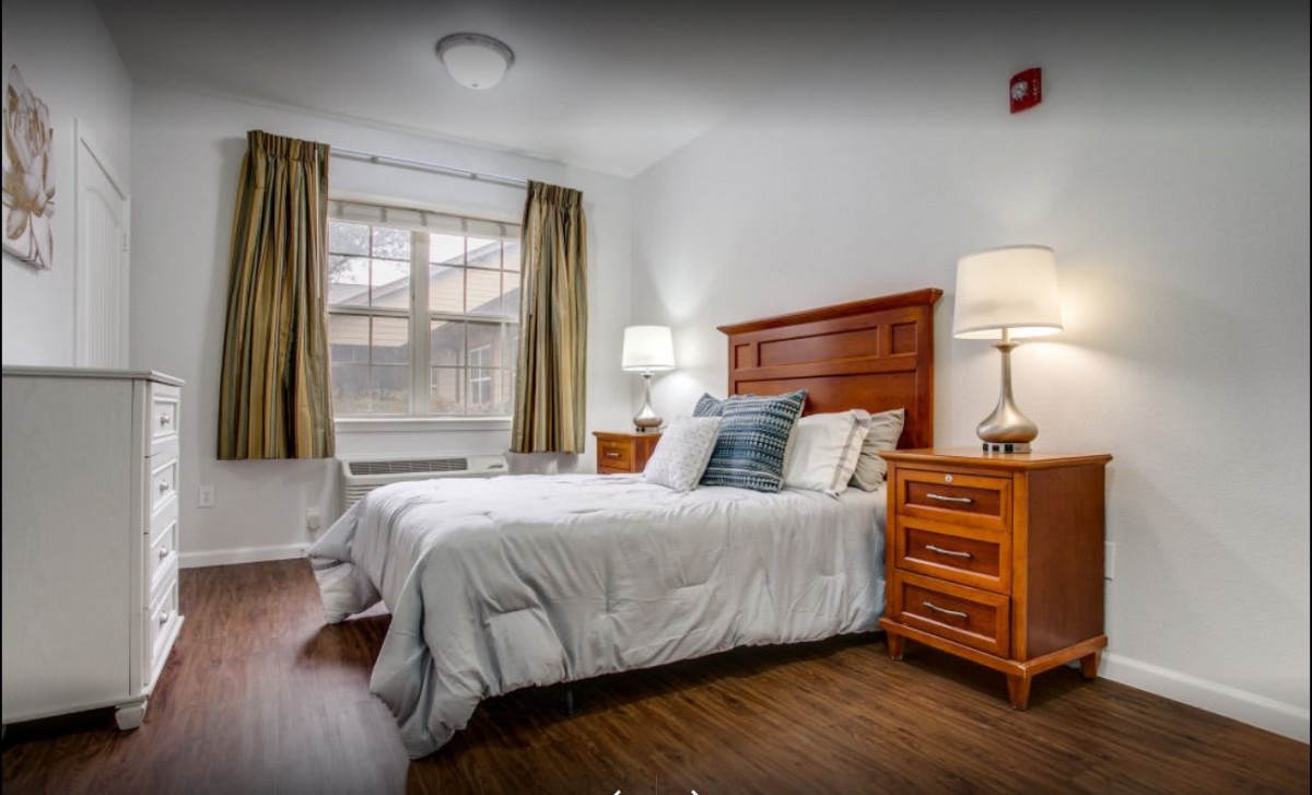 A cozy bedroom with a comfortable bed, wooden nightstands, and warm lighting.