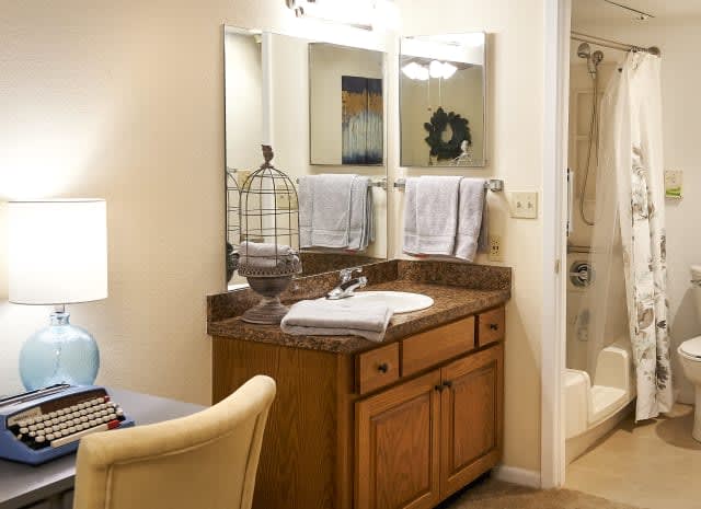 A tidy bathroom with a wooden vanity and mirror, featuring decorative elements and neatly arranged towels.