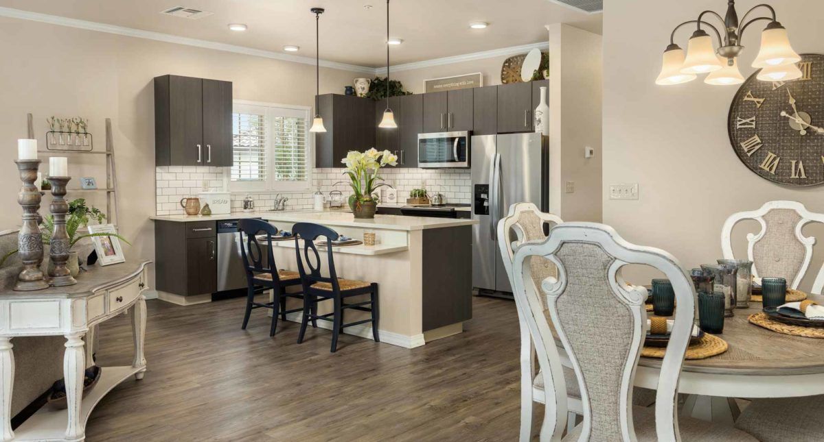 A modern kitchen interior with an island, pendant lighting, and stainless steel appliances.