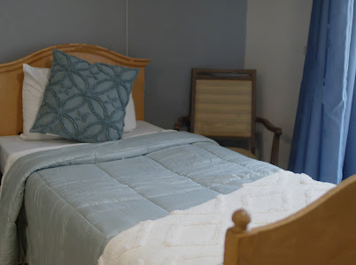 A cozy bedroom featuring a neatly made bed with a decorative pillow and a simple chair in the corner.