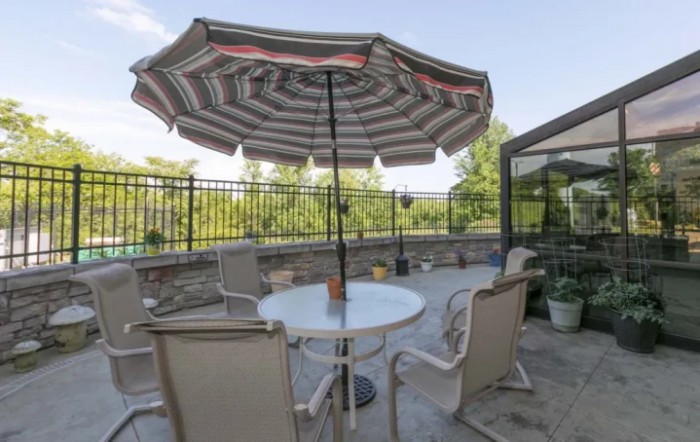 A cozy outdoor patio with a table, chairs, and a large umbrella.
