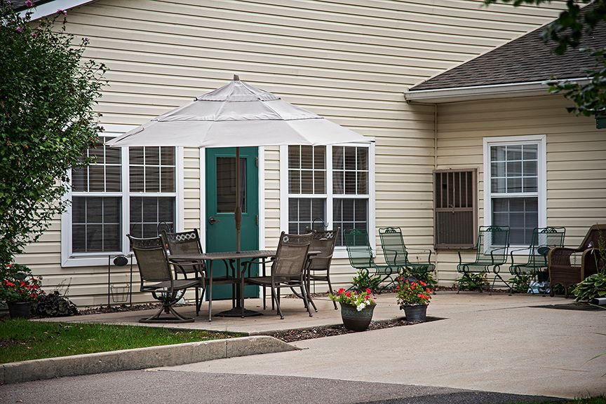 A cozy outdoor patio area with chairs and a table near a house.
