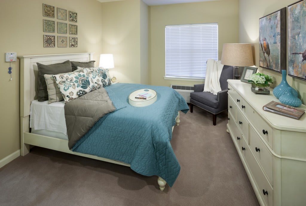 A modern bedroom with a neatly made bed, featuring blue accents and stylish decor.