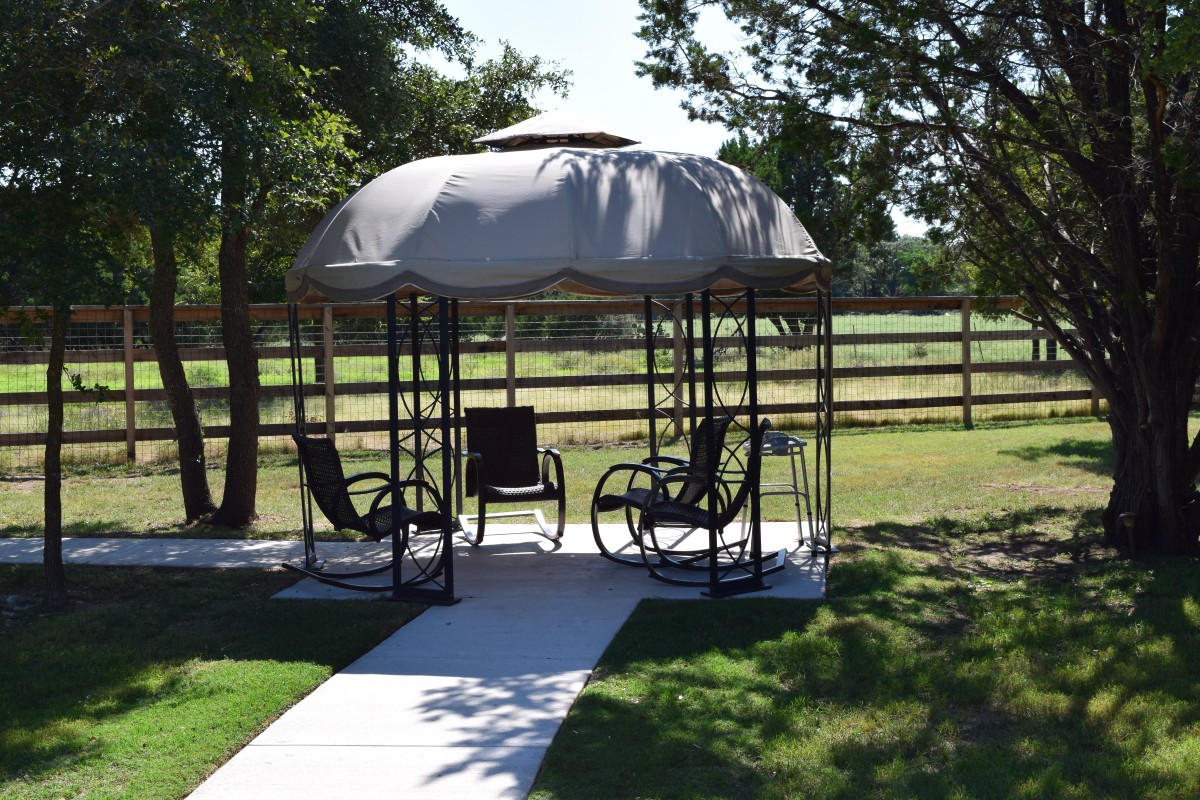 A cozy gazebo with chairs, offering shade and relaxation in a garden setting.
