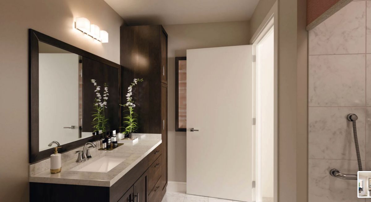 A modern bathroom with a sleek design featuring a large mirror, dark cabinets, and minimal decor.