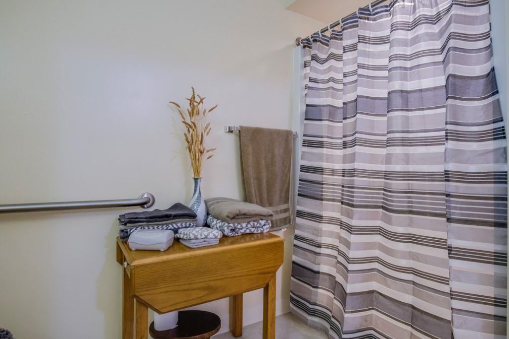 A neatly organized bathroom with a striped shower curtain and decorative items on a wooden table.