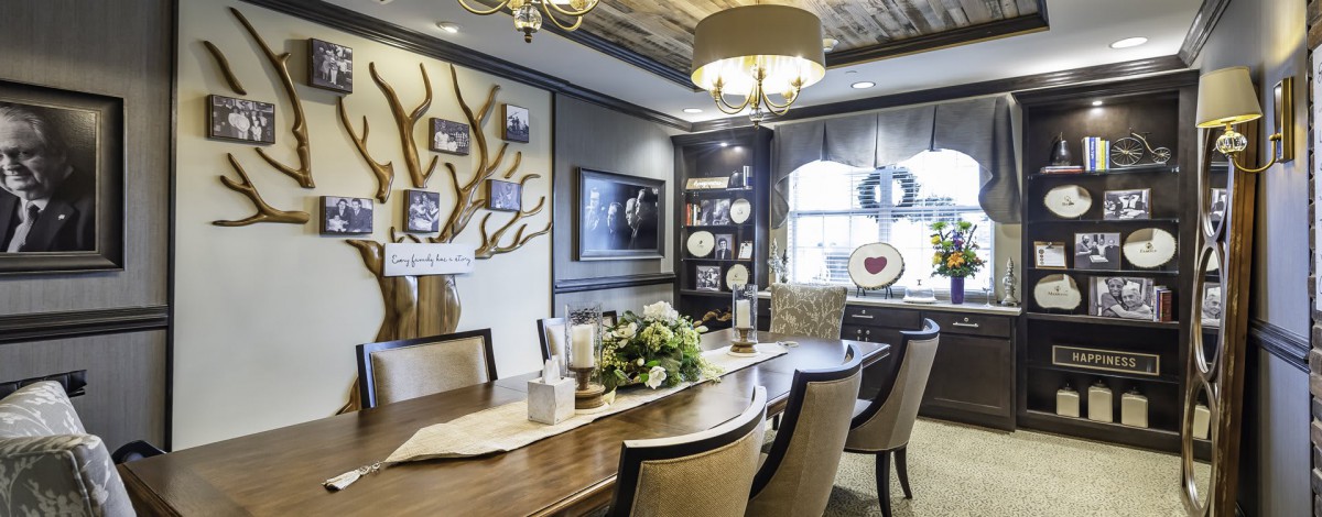 A beautifully designed dining room featuring a long wooden table, elegant chairs, and decorative elements including wall art and plates.