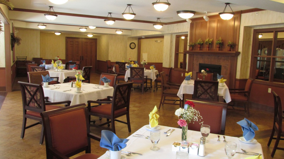 An elegant dining room with neatly arranged tables and chairs, featuring place settings and floral decorations.
