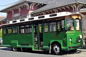 A green trolley bus parked at a station.