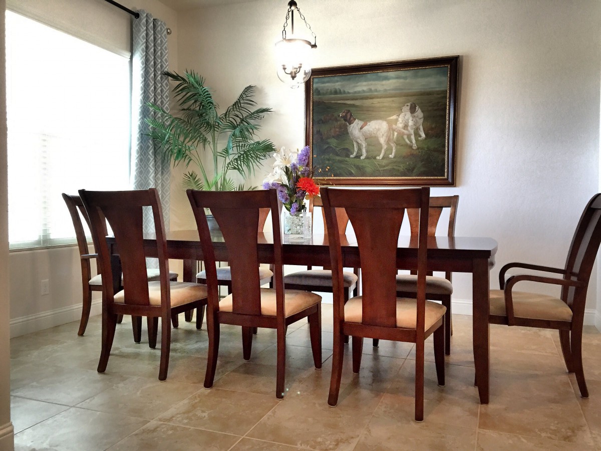 A well-decorated dining room featuring a wooden table and chairs, adorned with plants and wall art.